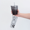 Carbon Duo Magnetic Grip ring looped over a finger, carrying a phone alongside a drink
