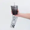 Carbon Duo Magnetic Grip ring looped over a finger, carrying a phone alongside a drink